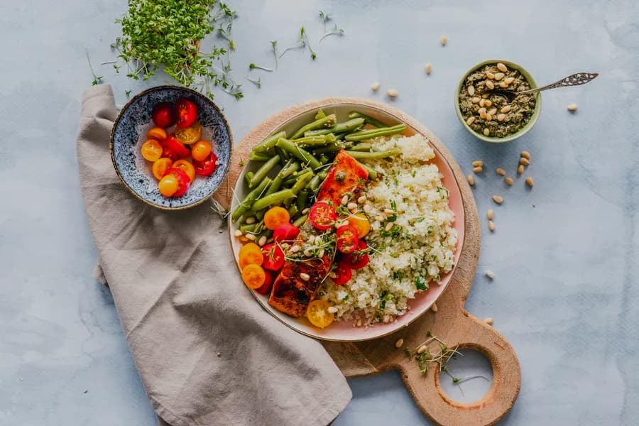 Neatly prepared high-protein meal prep glass containers on dark kitchen surface with fresh ingredients