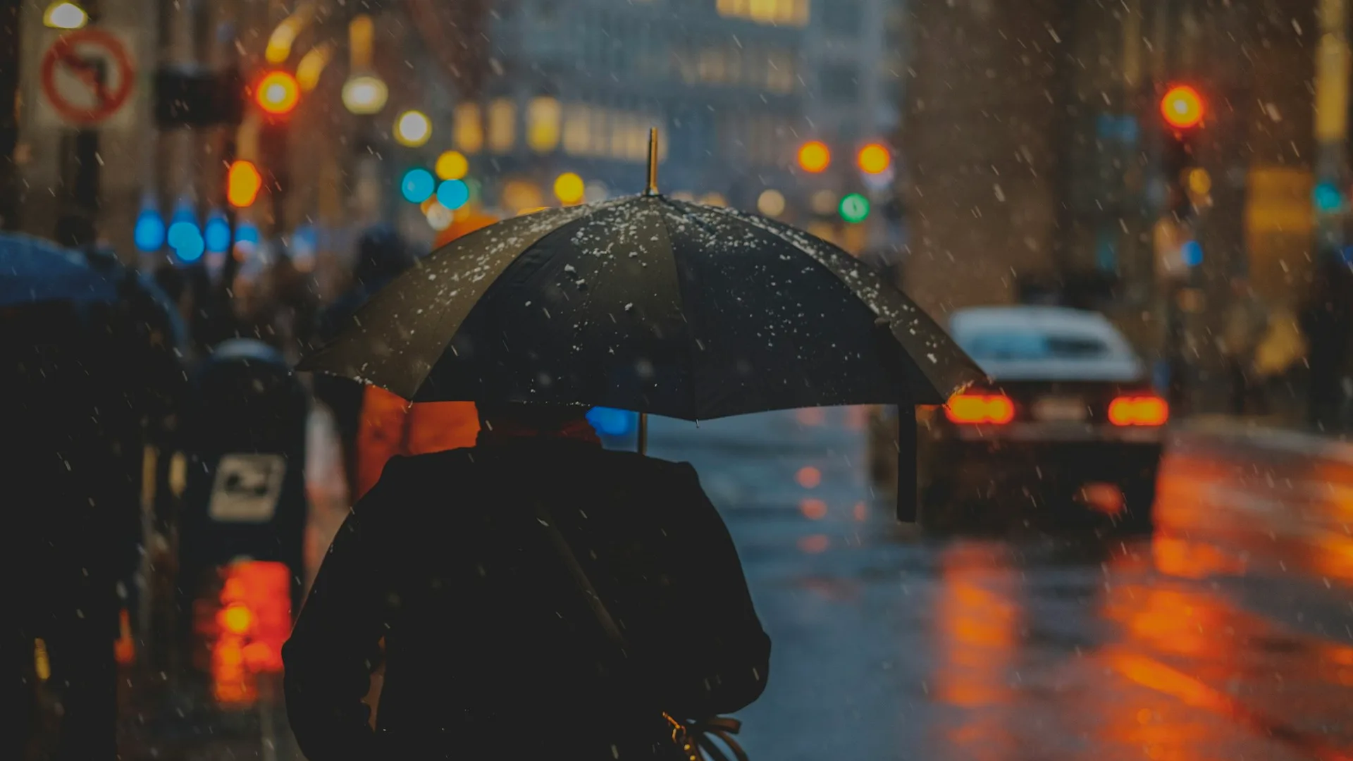 Creator working late at night on digital products in a rain-streaked urban studio